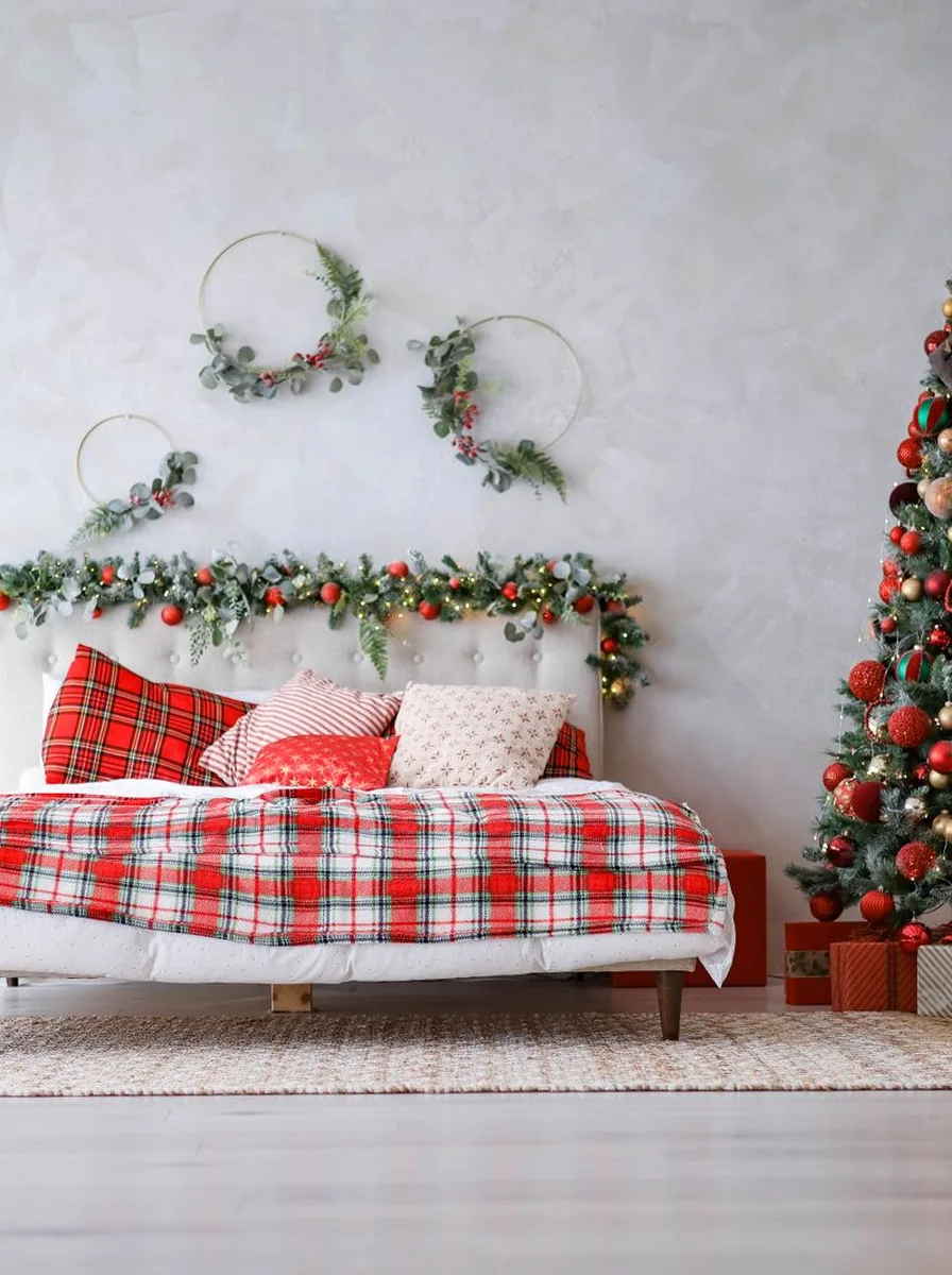 Bed with red plaid bedding, garland headboard, and Christmas tree