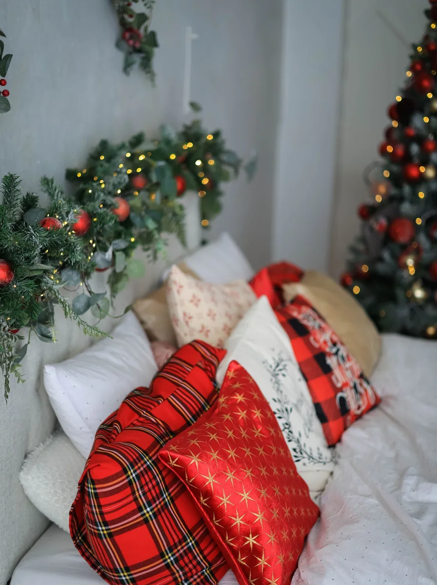 Bed with red plaid pillows and a garland-draped headboard