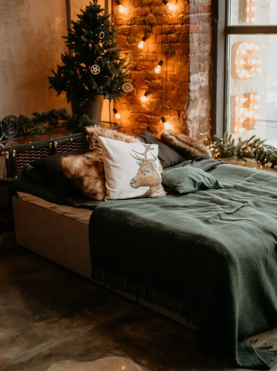Bedroom with dark green bedding, brick wall, and Christmas tree
