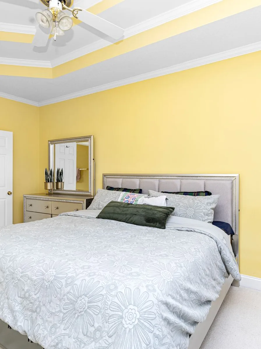 Bedroom with cheerful yellow walls and white bed