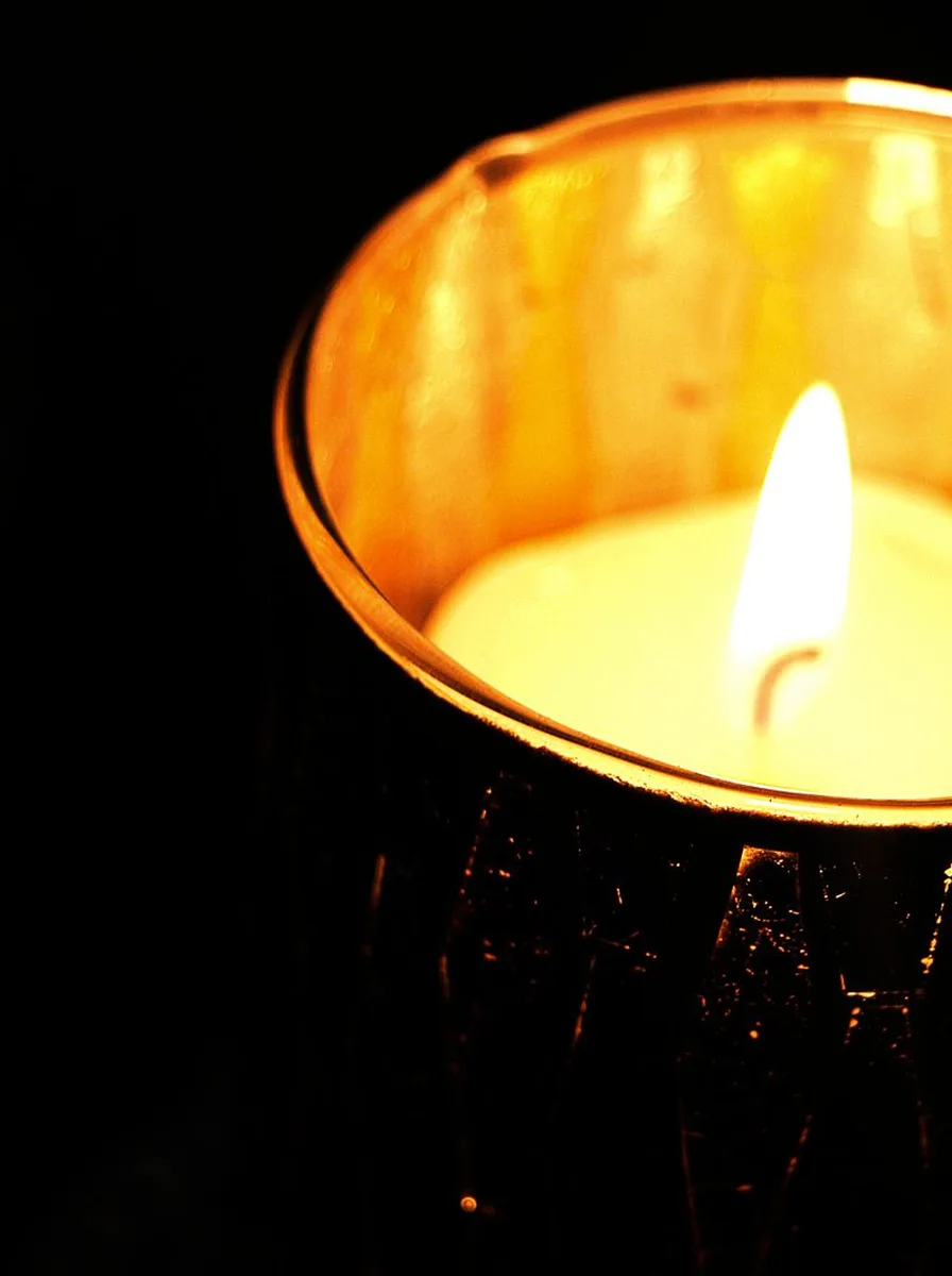 Black hurricane candle lamps with pillar candles on the edge of a bathtub