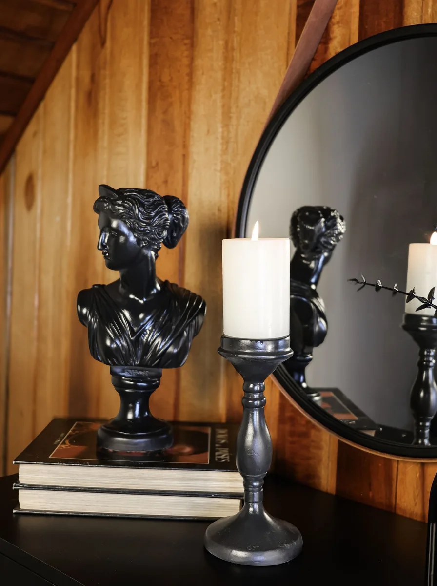 Gothic-style black candelabra with dark tapers on a bedroom dresser