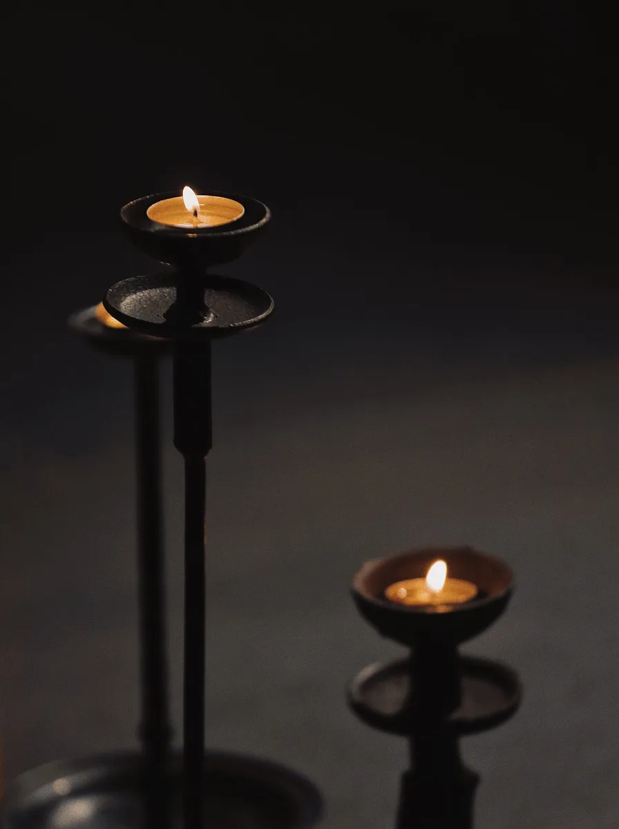 Black candle holders on a white marble bathroom counter with folded towels