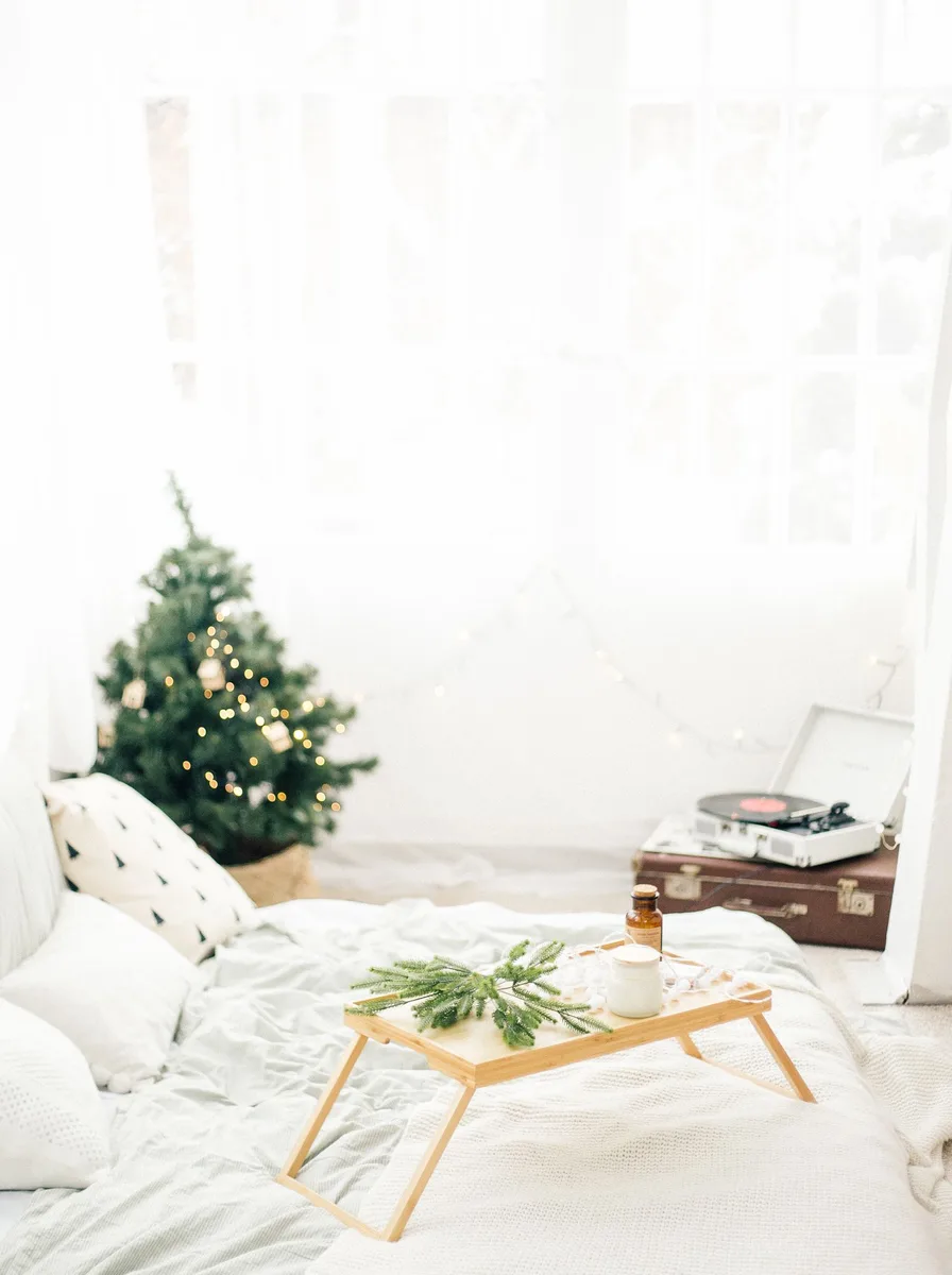 Bright white bedroom with a small Christmas tree