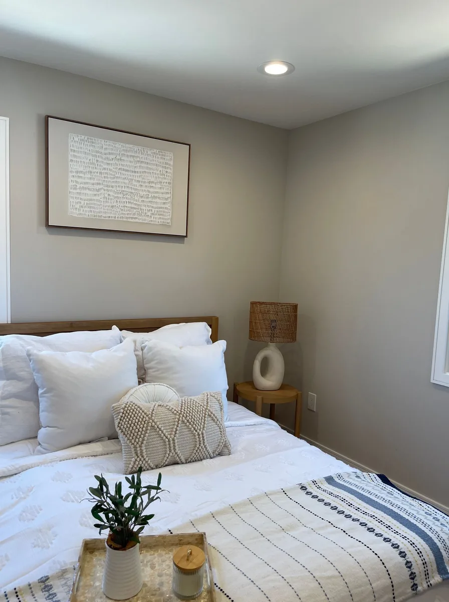 Beautifully styled bed with gallery wall frames and cozy neutral bedding