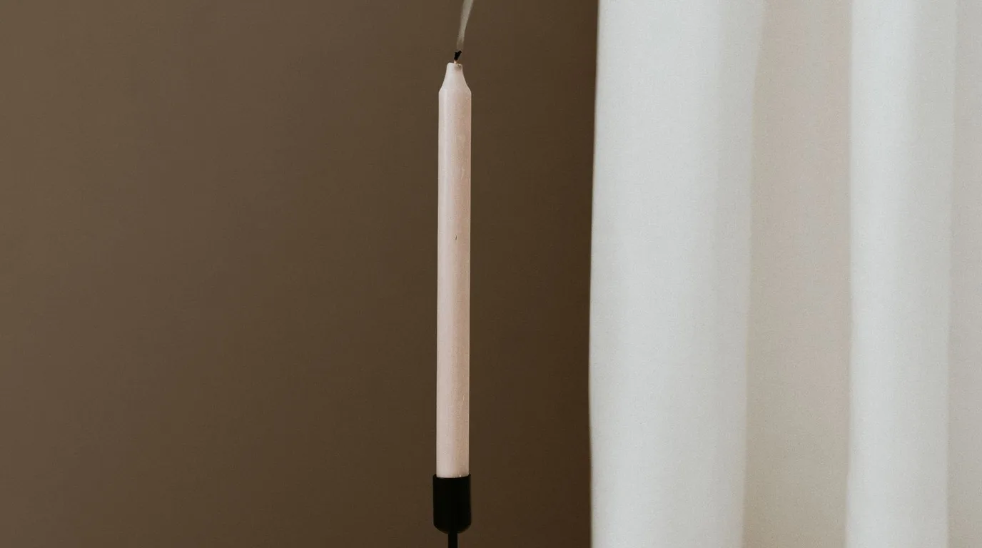 Modern living room shelf styled with sculptural matte black and ceramic candle holders lit at dusk