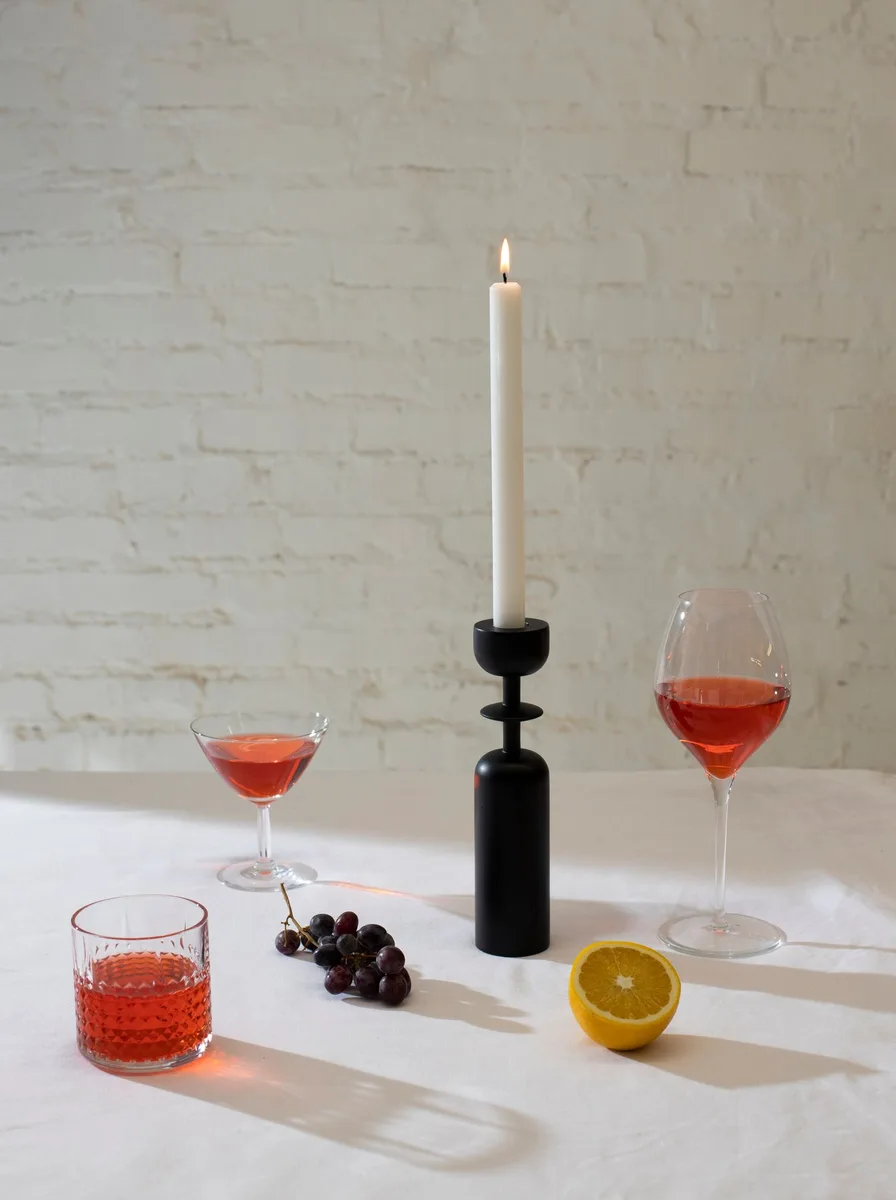 Gray concrete pillar candle holders of staggered heights on a minimalist shelf