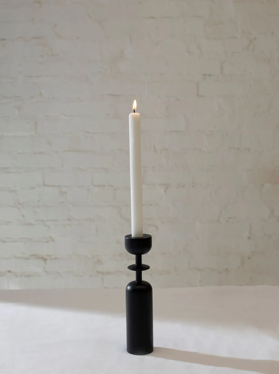 Cream-colored ribbed ceramic candle holders holding lit tea lights on a sideboard