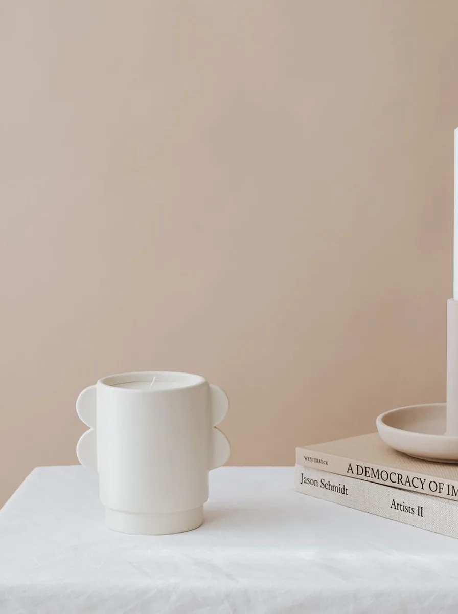Three small tea light holders on white marble bases glowing on a bedroom nightstand