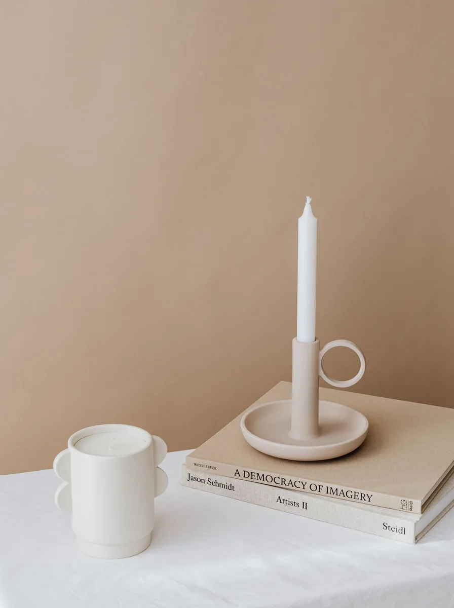 Pair of slim black metal taper holders on either side of a modern fireplace mantel