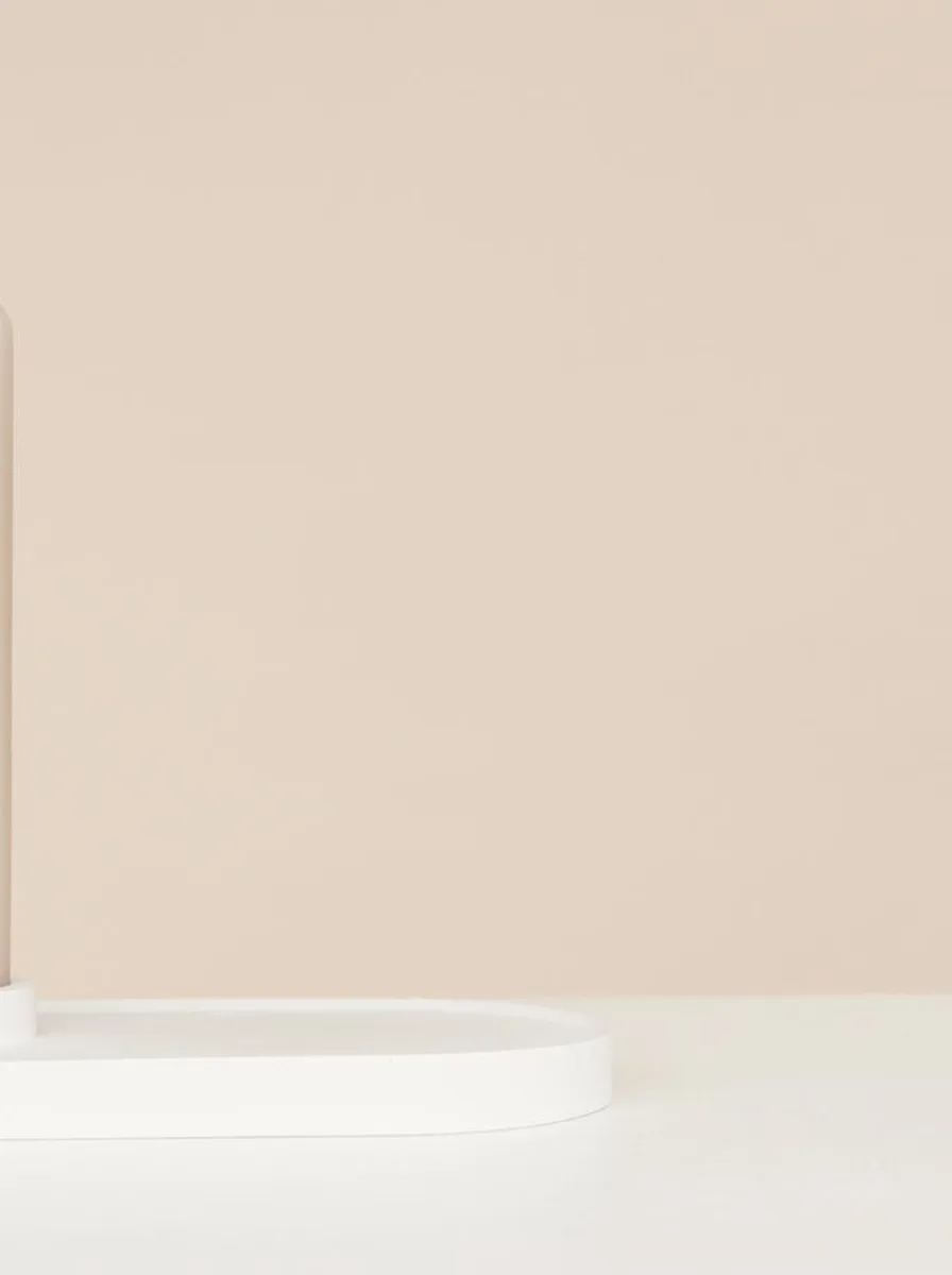 Muted sage green ceramic candle holders on a bedroom dresser beside a small plant