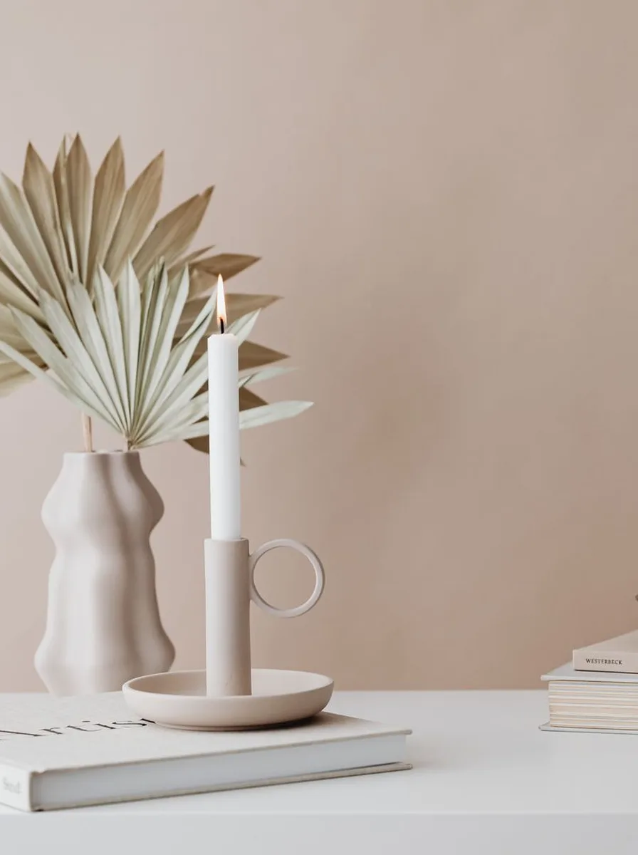 Curved silhouette candle holders in warm taupe tucked between books on a bookshelf