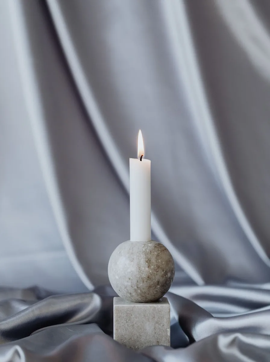Rust-orange ceramic candle holders with tapers on a mantel decorated for autumn