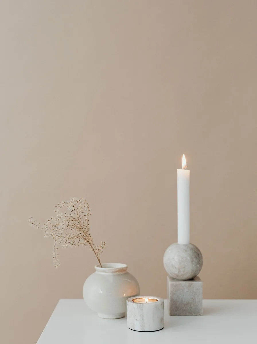 Minimalist white ceramic tea light holders on a bathroom vanity beside rolled towels