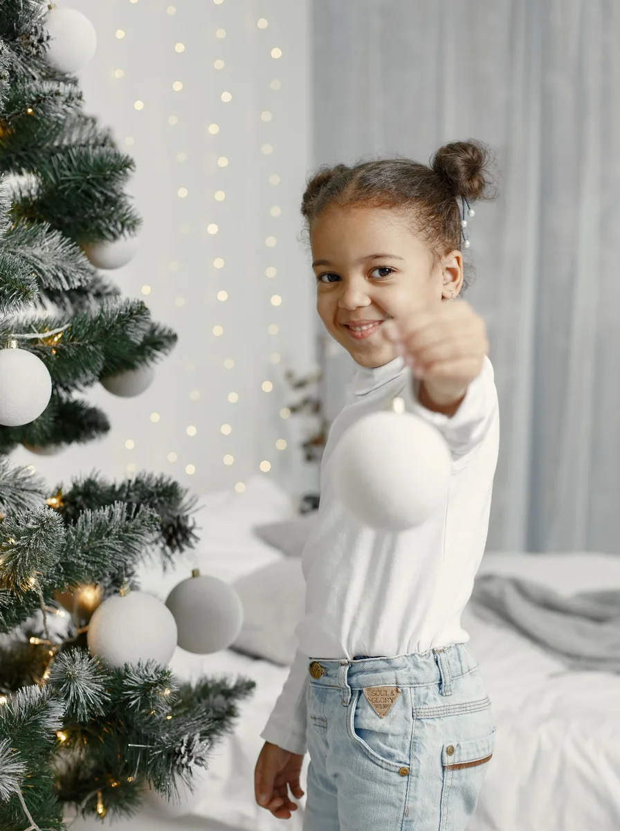 Child standing beside a decorated Christmas tree