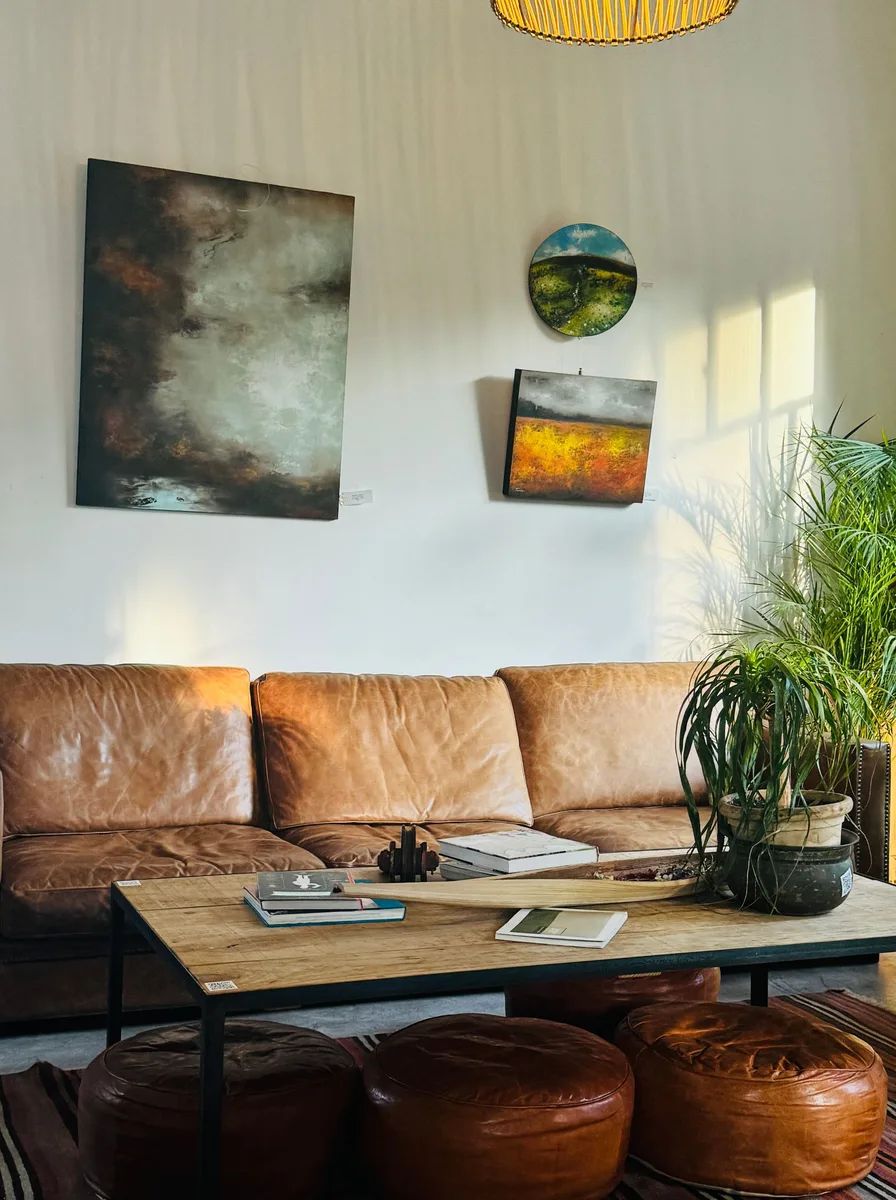 Living room with tan leather sofa and small colourful wall art hung above it