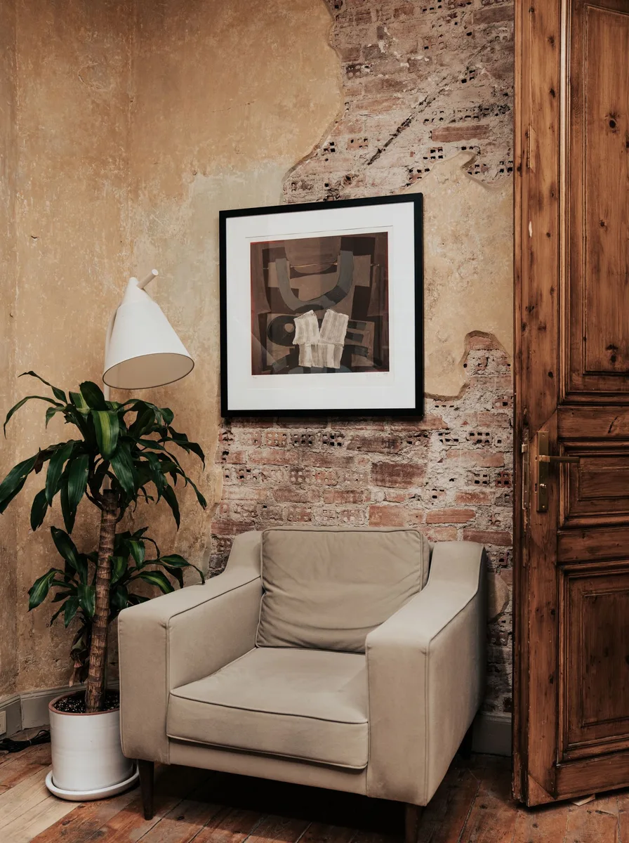 Rustic textured wall with framed black-and-white art, armchair and potted plant