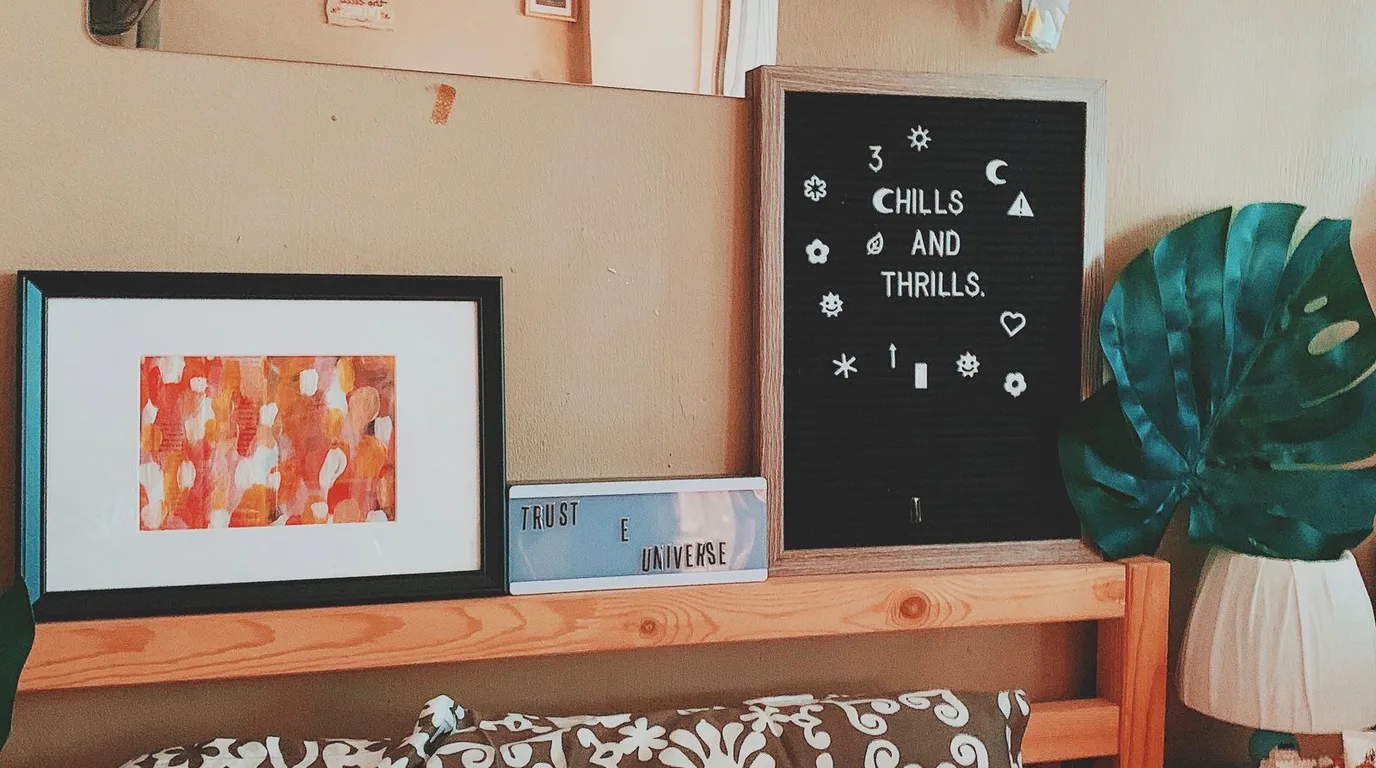 Wooden shelf styled with framed abstract art and a letter board