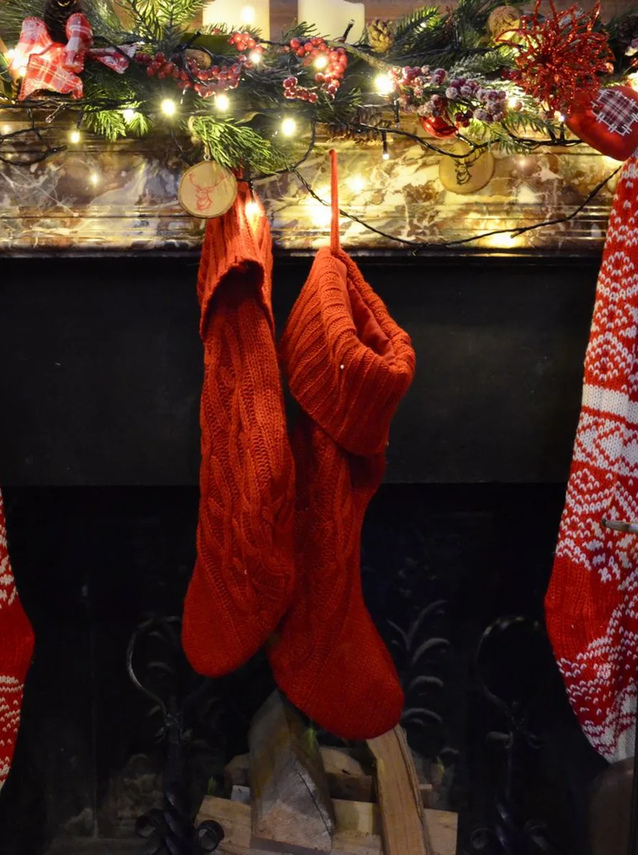 Fireplace mantel with Christmas garland, stockings, and lights