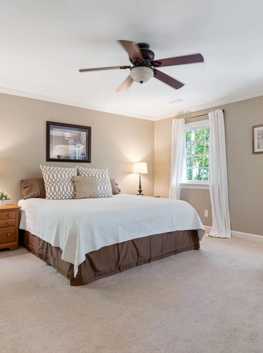 Sheer white curtains billowing in a white bedroom