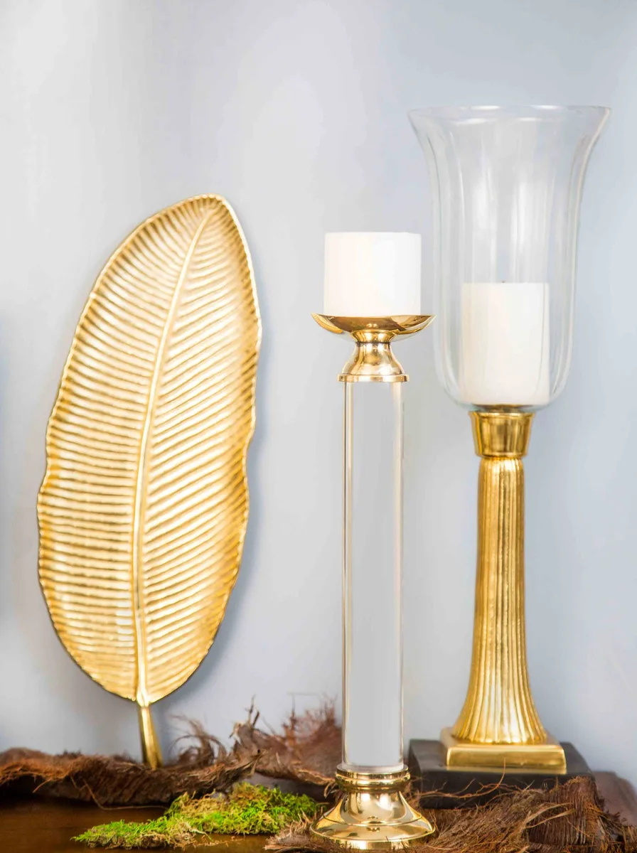 Three tall brass candlesticks holding lit cream taper candles on a set dining table