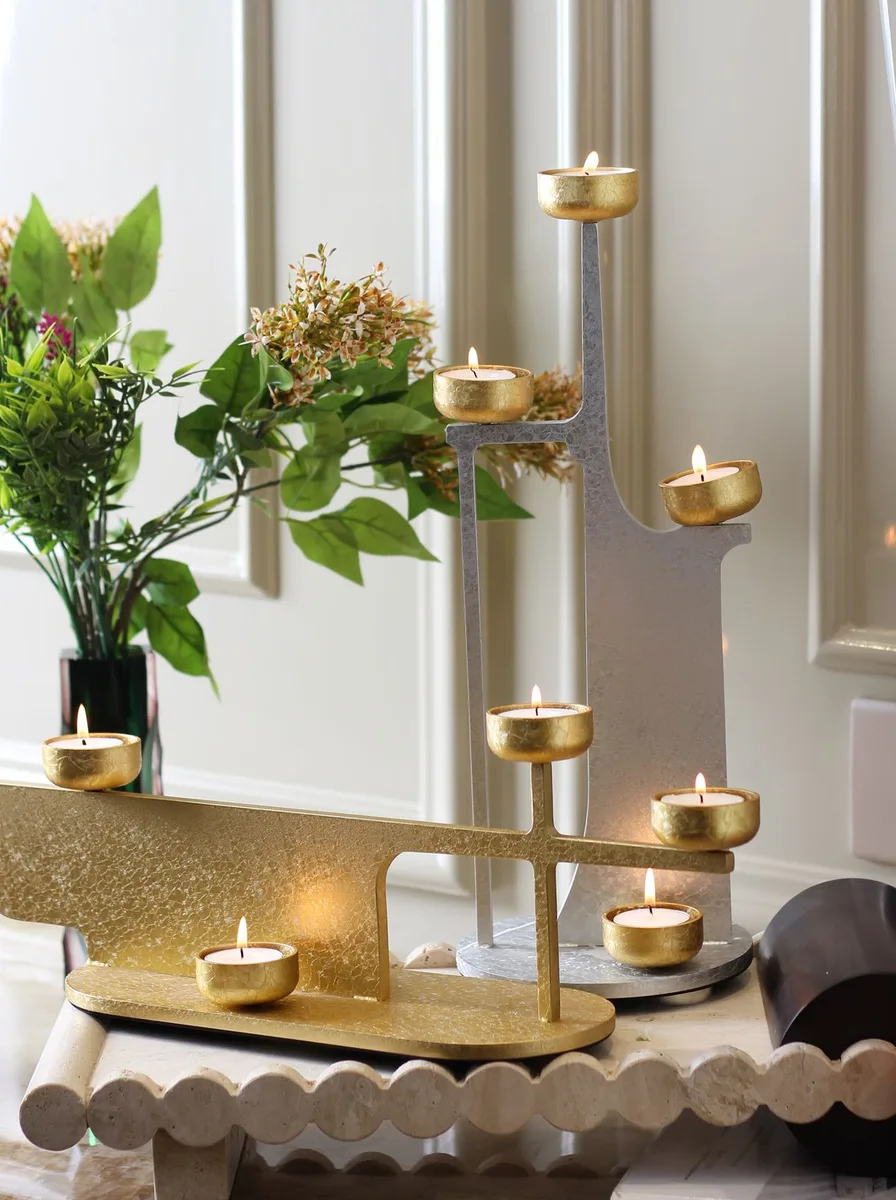 Gold pillar candle holders of different heights grouped on a round mirrored tray