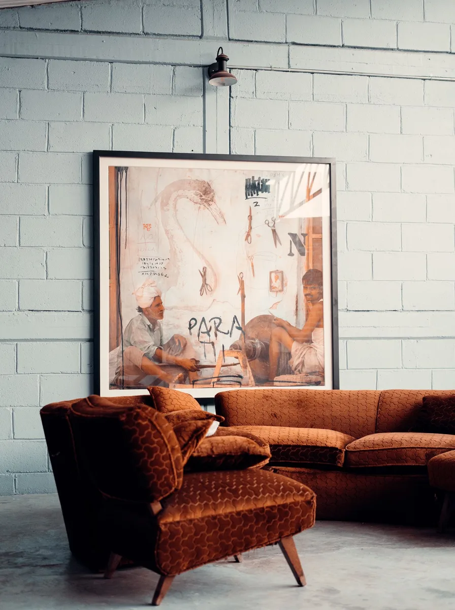 Large framed artwork above a brown velvet sofa