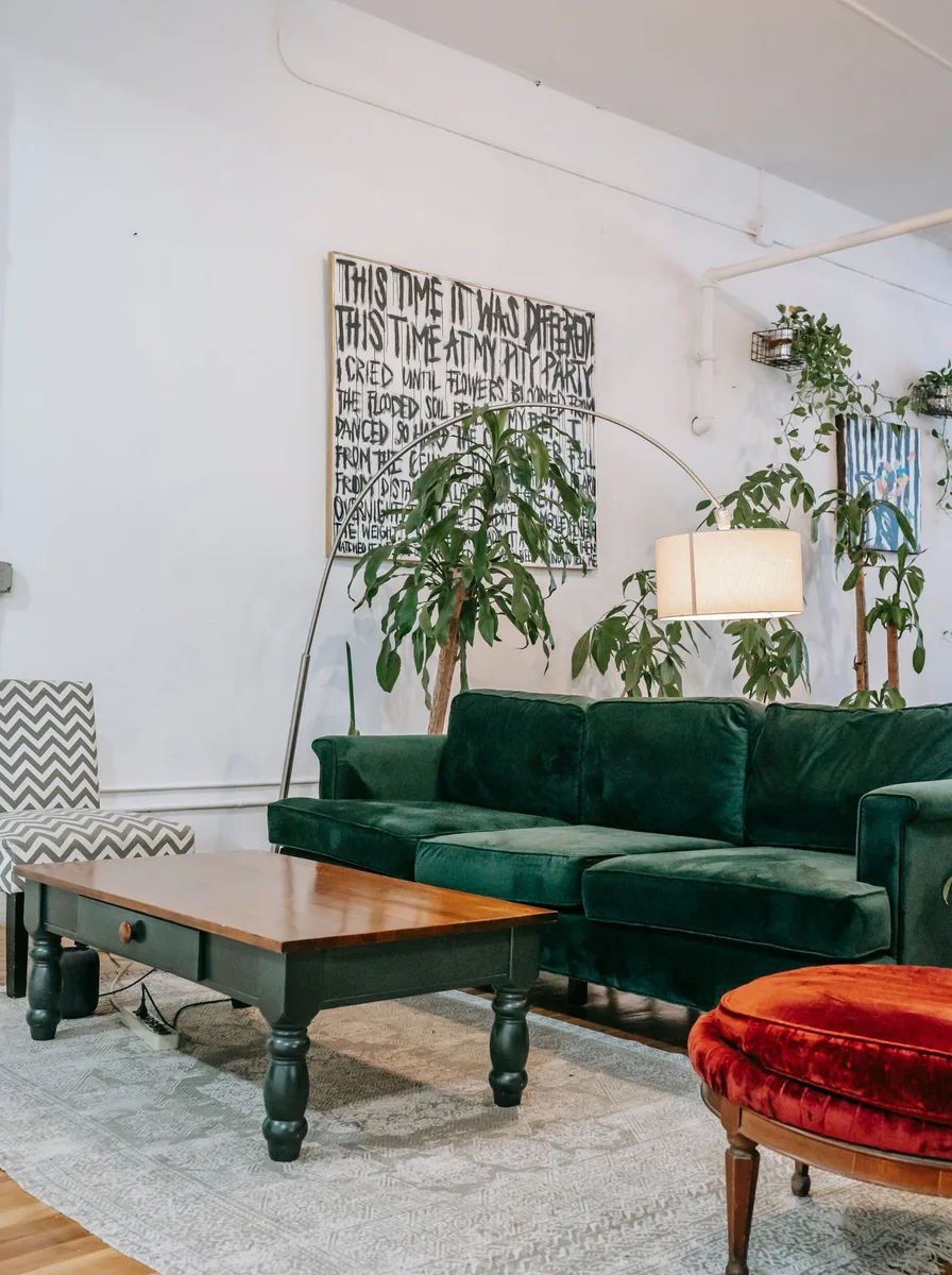 Oversized typography art above a green velvet sofa