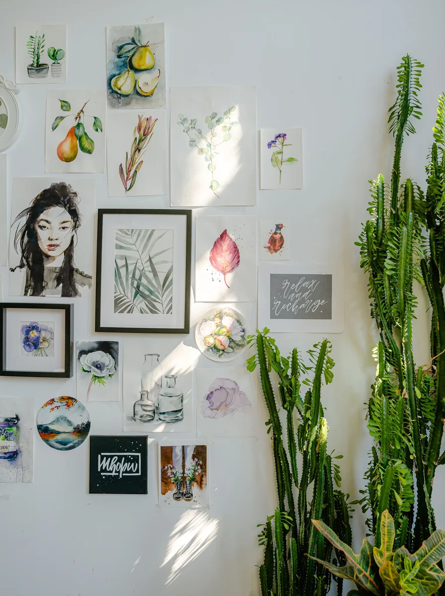 Sunlit wall of small prints styled with a tall cactus