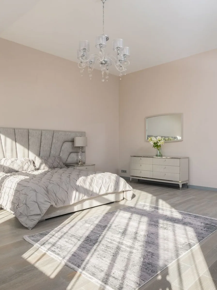 White bedroom with chandelier and sunlight