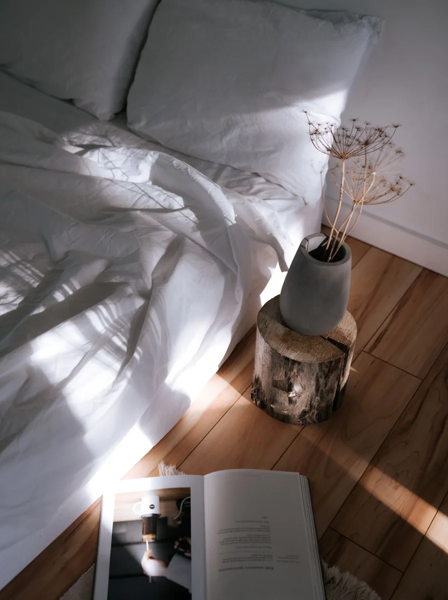 Sunlit bed with book and vase