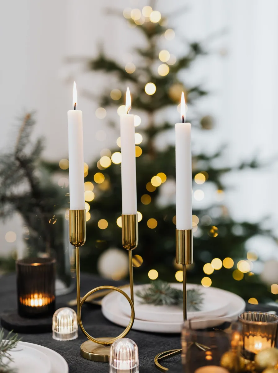 Lit candles on a table with a Christmas tree