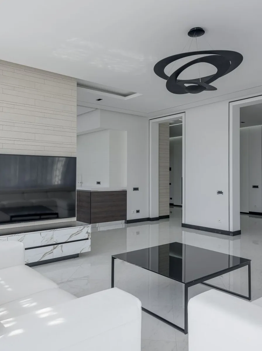 White sectional sofa floating on a black rug in a bright living room