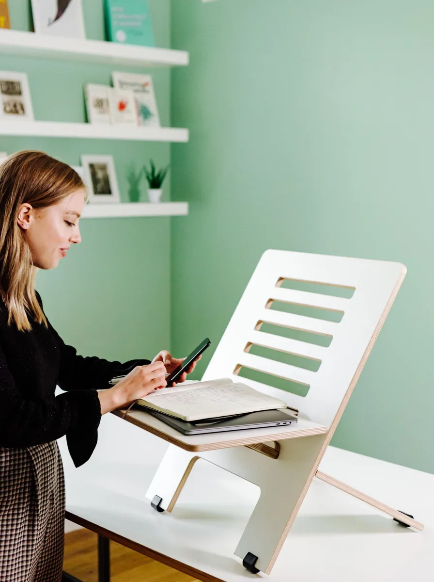 Perch stool beside a height-adjustable desk