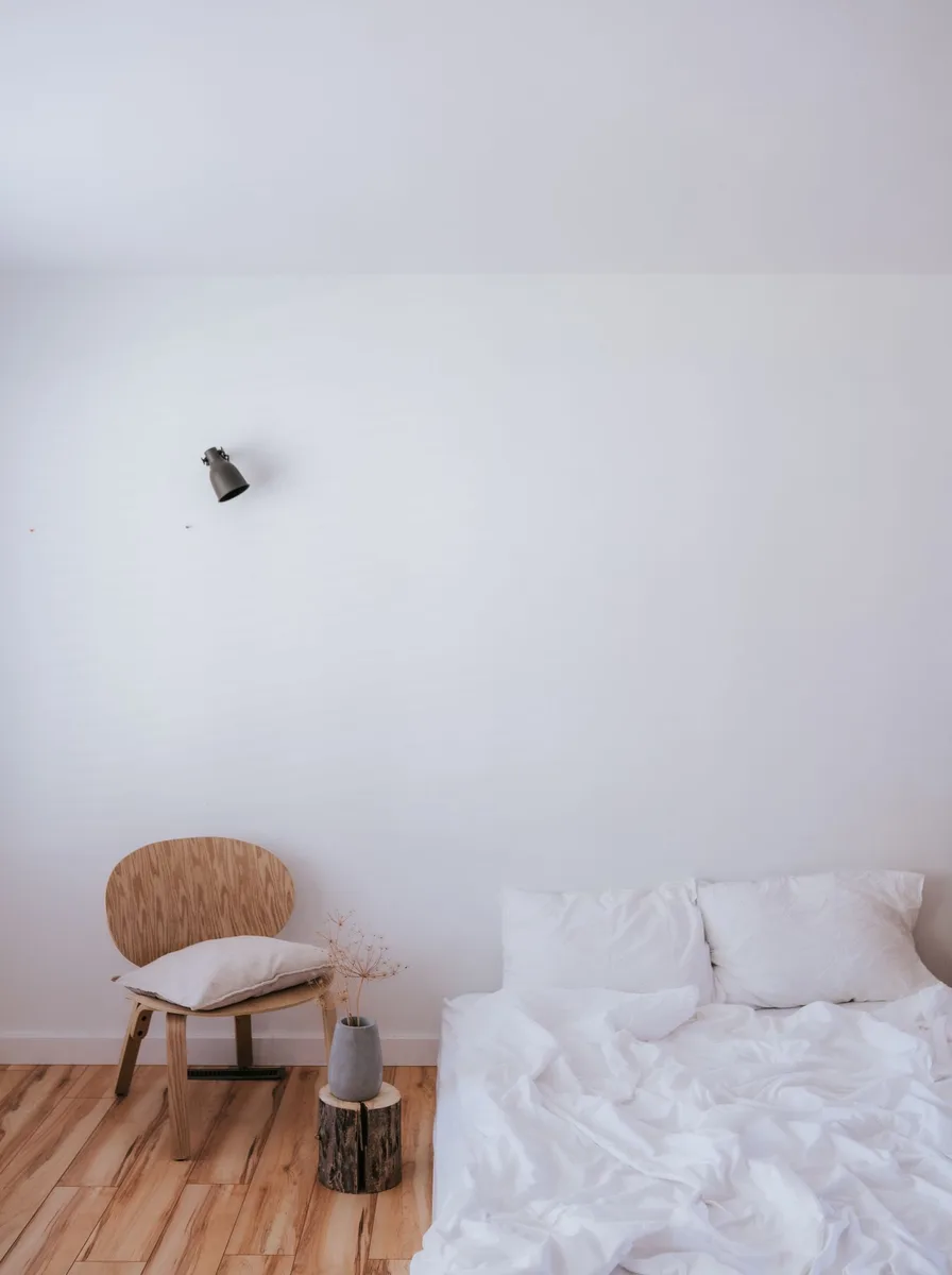 Minimal white bedroom with a single chair and uncluttered surfaces