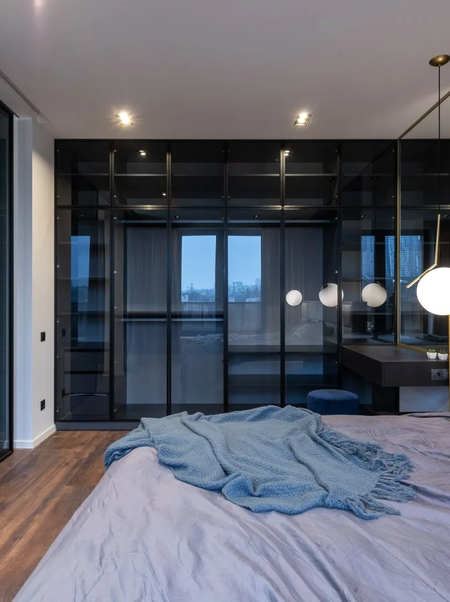 Contemporary bedroom with dark wardrobe wall and blue-grey bedding