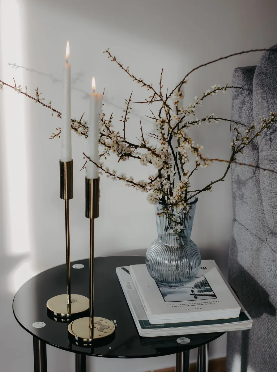Minimalist candle holder beside a trailing plant and wooden tray