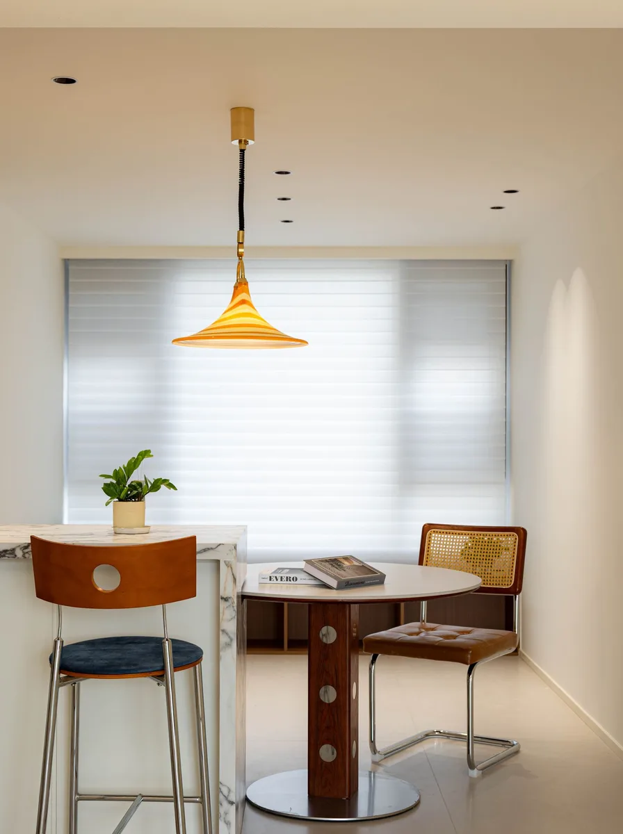 Minimal dining nook with an orange cone pendant light and round table