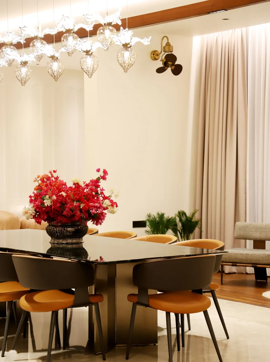 White modern dining room with sculptural glass chandelier and red flower bouquet