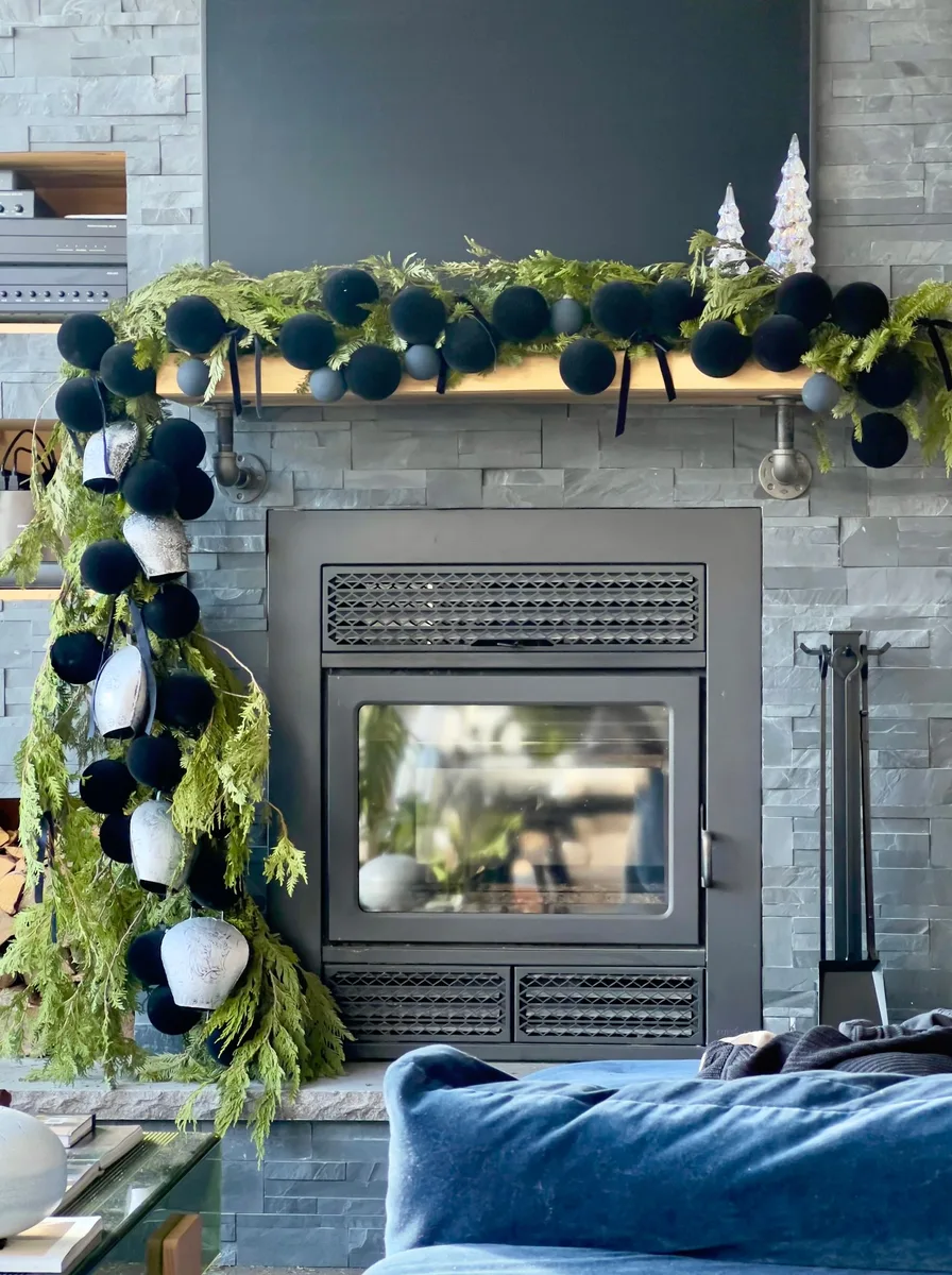 Modern fireplace with navy pom-pom garland and greenery