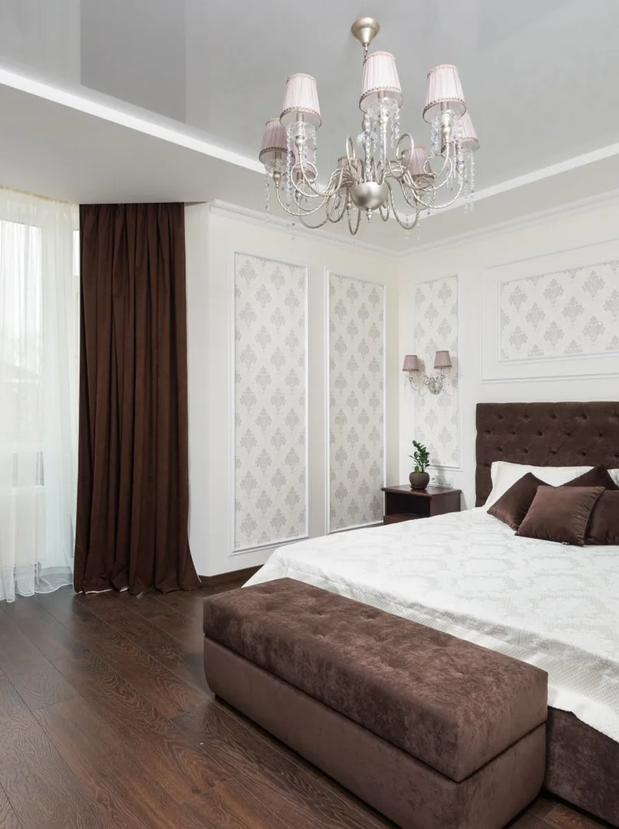 Brown bedroom with chandelier and bench