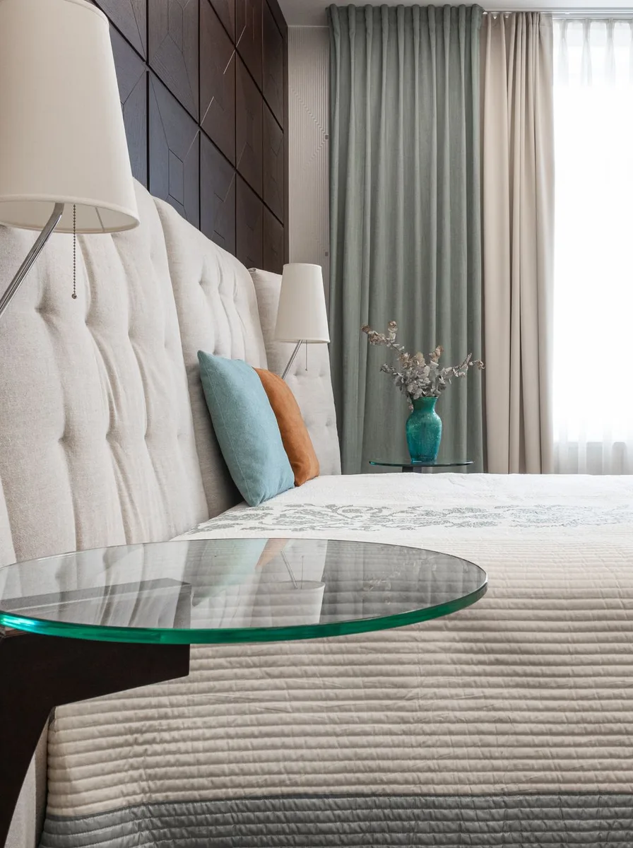 White bed with glass side table and colorful pillows