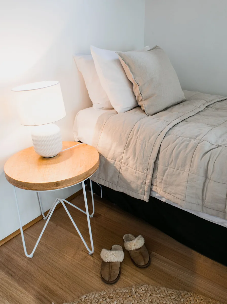 Cozy beige bed with wooden side table