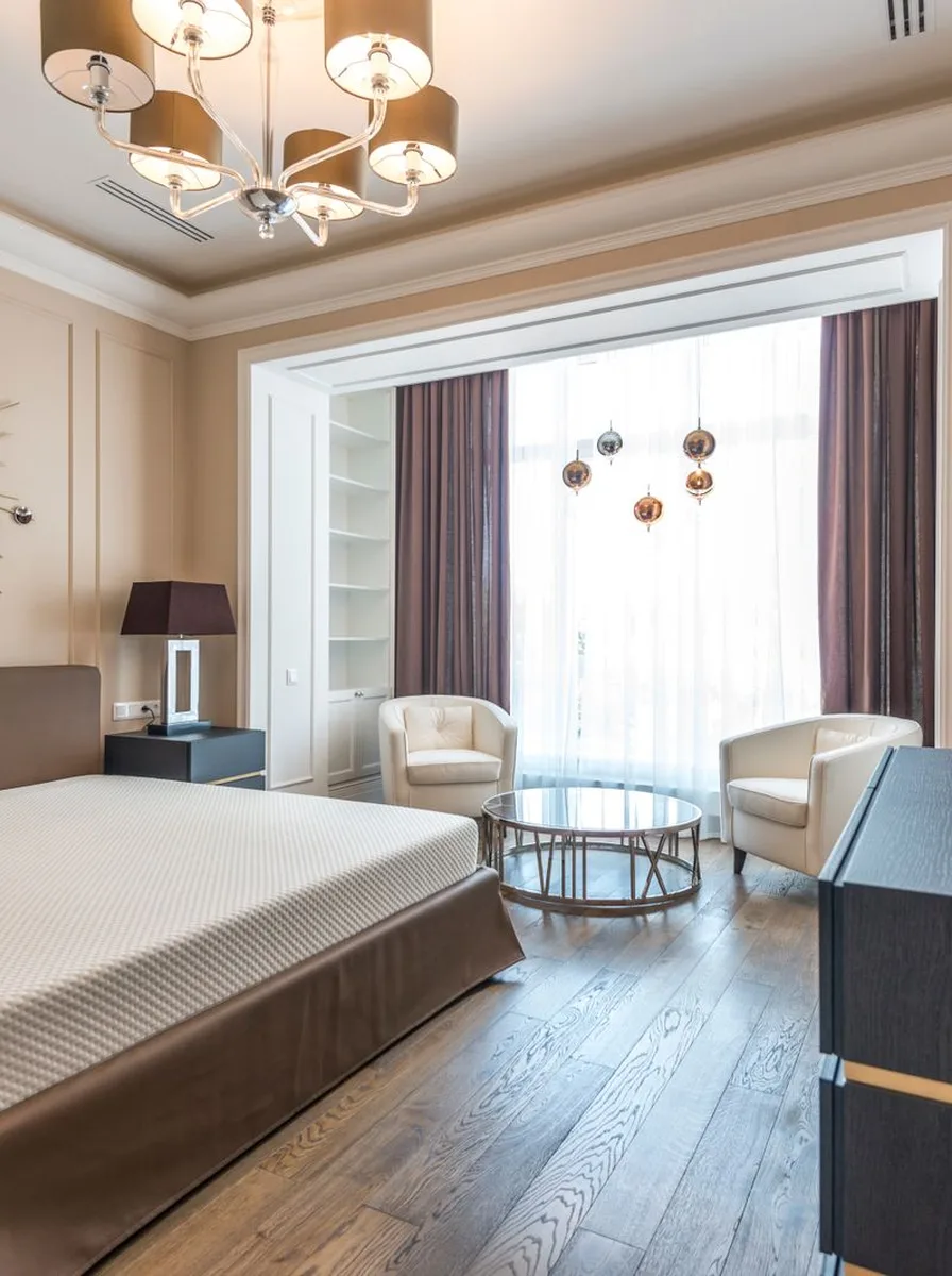 Beige bedroom with sitting area and chandelier