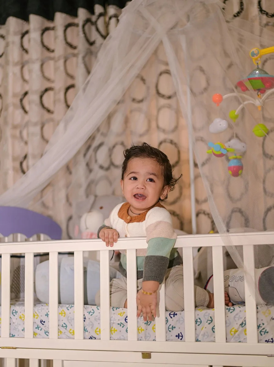 Smiling baby in a white crib with a sheer canopy