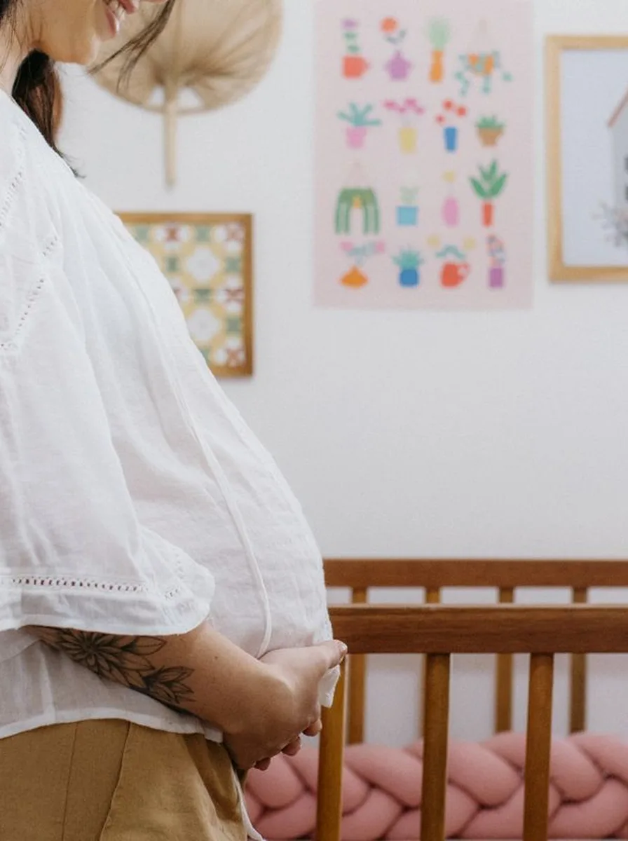 Pregnant woman standing beside a nursery crib