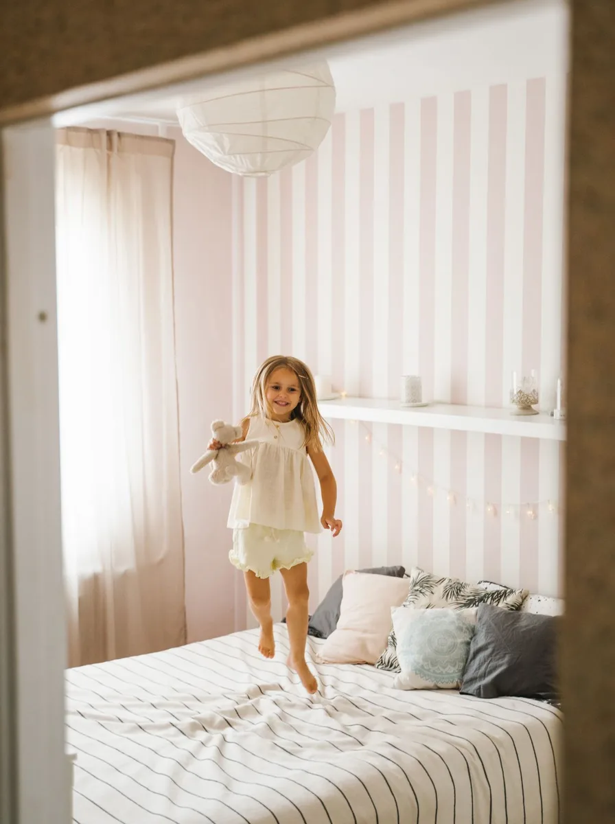 Girl jumping on a bed in a nursery