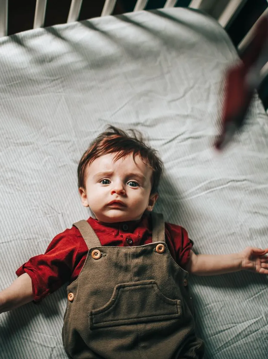 Toddler in overalls in a bright room
