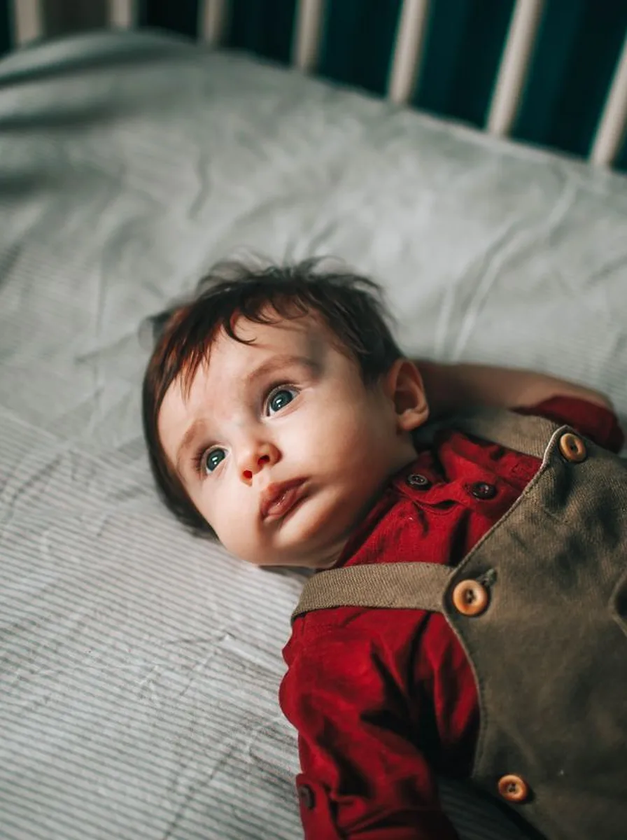 Toddler in overalls looking up