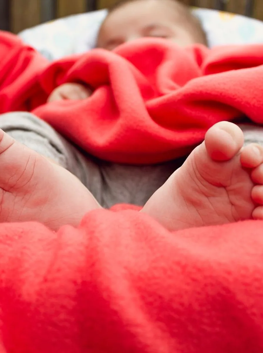 Baby feet wrapped in a red knit blanket